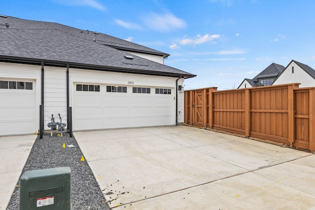 garage with driveway, fence, and a gate