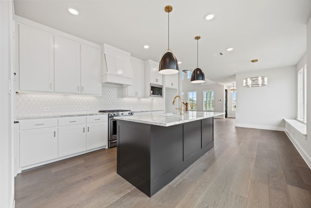 kitchen featuring stainless steel appliances, backsplash, white cabinets, wood finished floors, and premium range hood