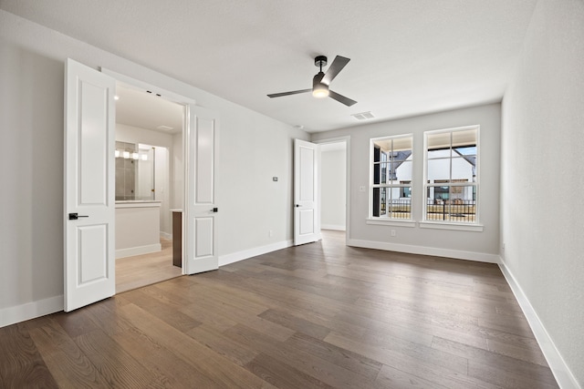 unfurnished bedroom featuring dark wood-type flooring, ensuite bath, visible vents, and baseboards