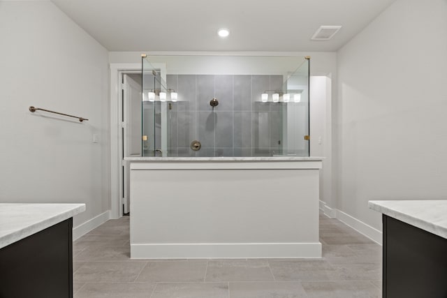 bathroom with baseboards, visible vents, walk in shower, and vanity