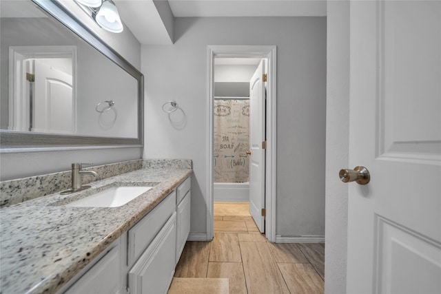 full bath featuring shower / tub combo, baseboards, wood finish floors, and vanity