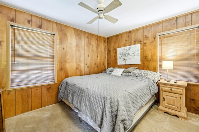 carpeted bedroom with wood walls and ceiling fan