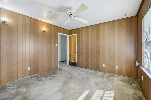 spare room with a ceiling fan, visible vents, carpet flooring, and wooden walls