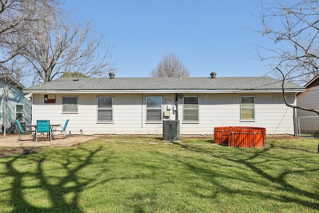 rear view of property featuring a yard, a shingled roof, a hot tub, a patio area, and cooling unit