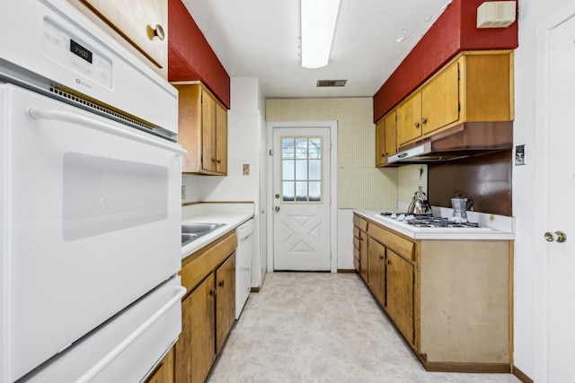 kitchen with visible vents, light countertops, brown cabinetry, white appliances, and under cabinet range hood