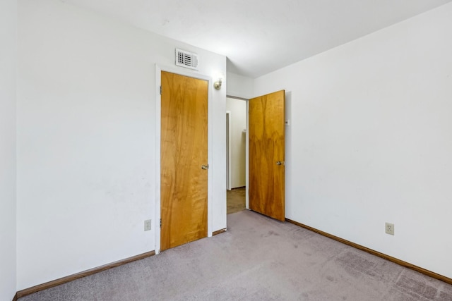 carpeted empty room featuring baseboards and visible vents