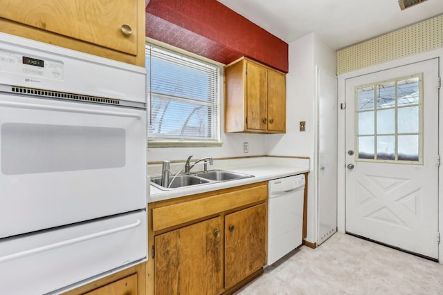 kitchen with light countertops, white appliances, a sink, and a wealth of natural light