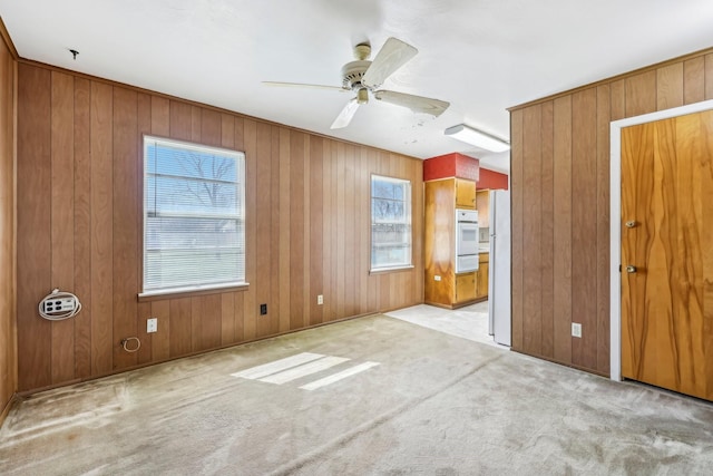 carpeted spare room featuring a ceiling fan and wooden walls