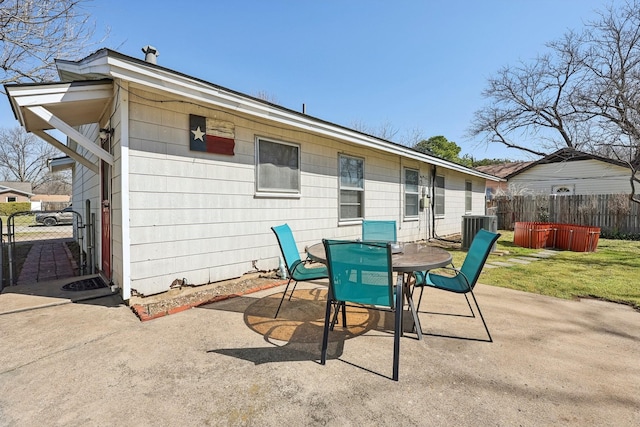 rear view of house featuring central AC unit, fence, outdoor dining area, a yard, and a patio area