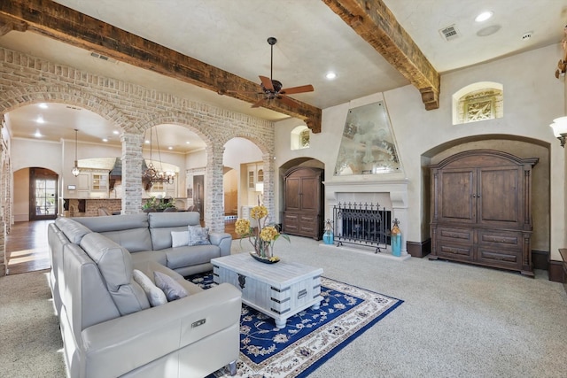 living room featuring a fireplace, visible vents, arched walkways, and beamed ceiling