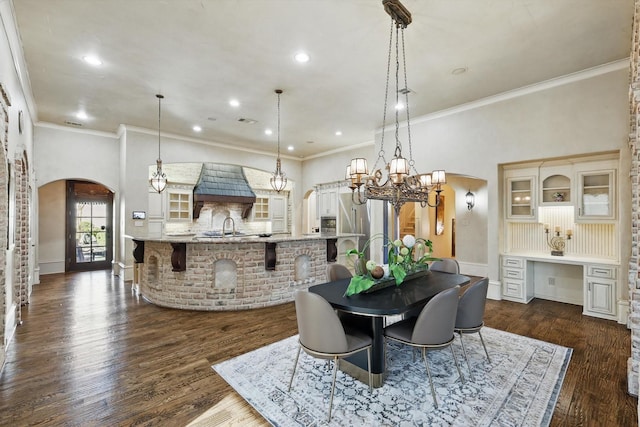 dining room featuring arched walkways, dark wood-style flooring, crown molding, recessed lighting, and baseboards