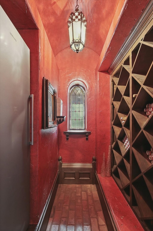 wine room with brick floor and vaulted ceiling