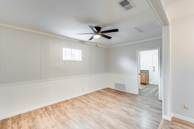 unfurnished room with crown molding, light wood-style flooring, visible vents, and attic access