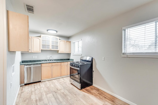 kitchen with visible vents, black gas range, stainless steel dishwasher, light brown cabinets, and a sink