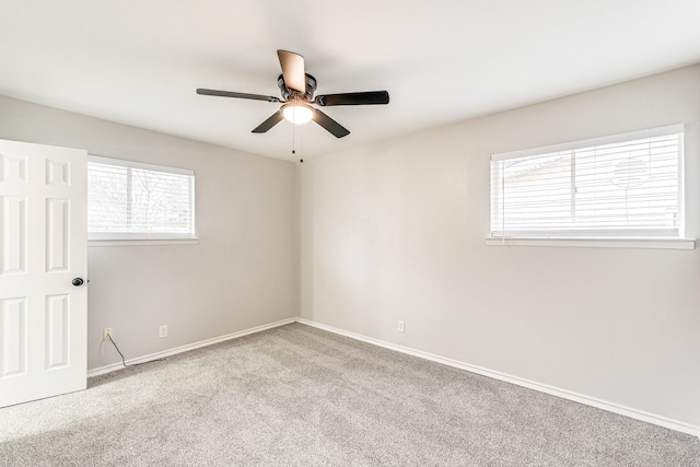 carpeted spare room featuring ceiling fan and baseboards