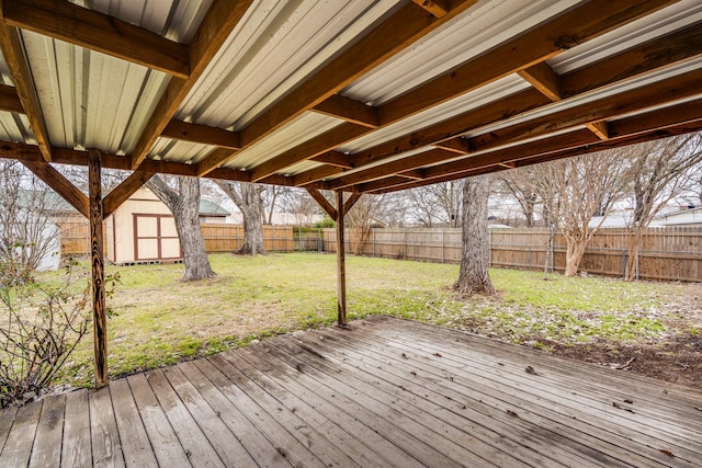 wooden deck with an outbuilding, a fenced backyard, a lawn, and a storage shed