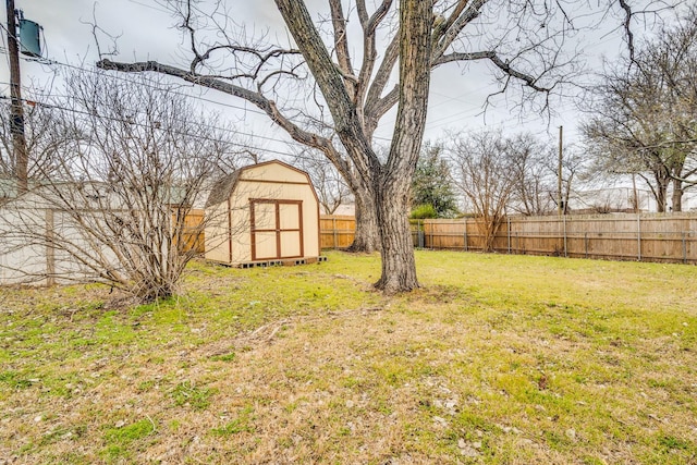 view of yard with a fenced backyard, a storage unit, and an outbuilding