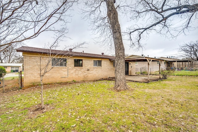 rear view of house featuring a patio, brick siding, a lawn, and fence