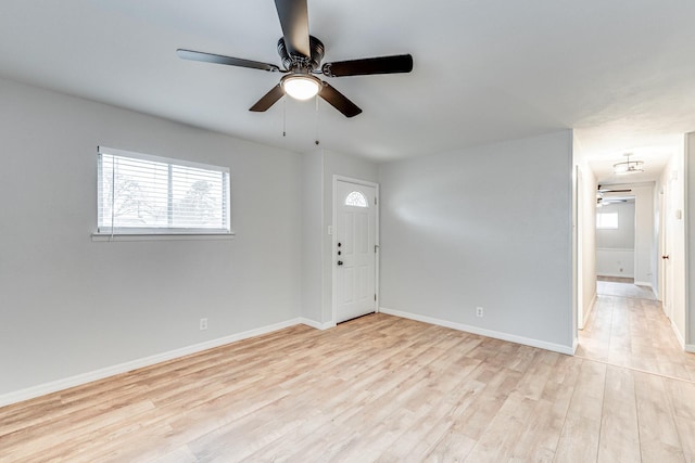 unfurnished room featuring light wood-type flooring, a ceiling fan, and baseboards