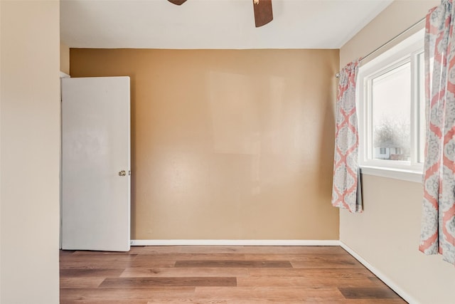 unfurnished room featuring ceiling fan, wood finished floors, and baseboards