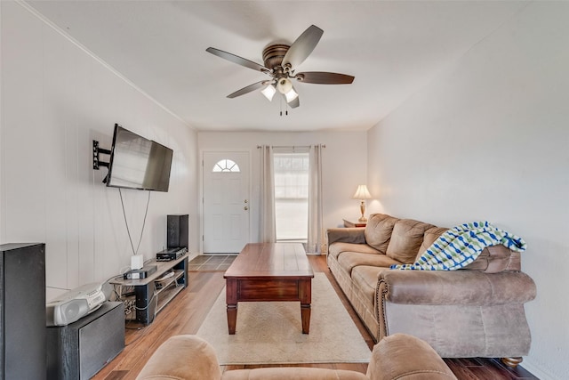 living room with crown molding, wood finished floors, and ceiling fan