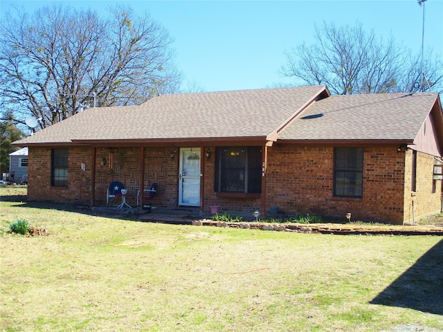 single story home with brick siding, a front yard, and a shingled roof