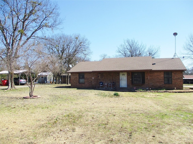 back of house featuring a carport, a lawn, and roof with shingles