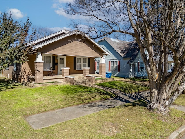 view of front of property featuring covered porch, brick siding, and a front yard