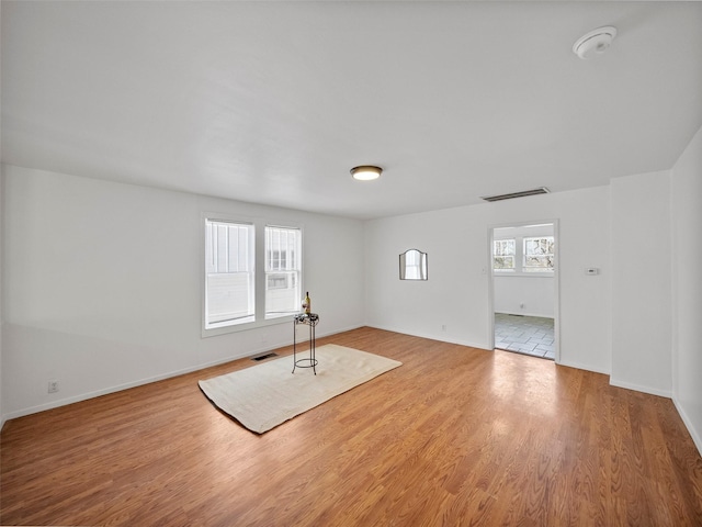 unfurnished room with visible vents, baseboards, and wood finished floors