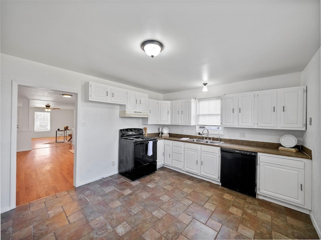 kitchen with dark countertops, stone finish flooring, a sink, and black appliances