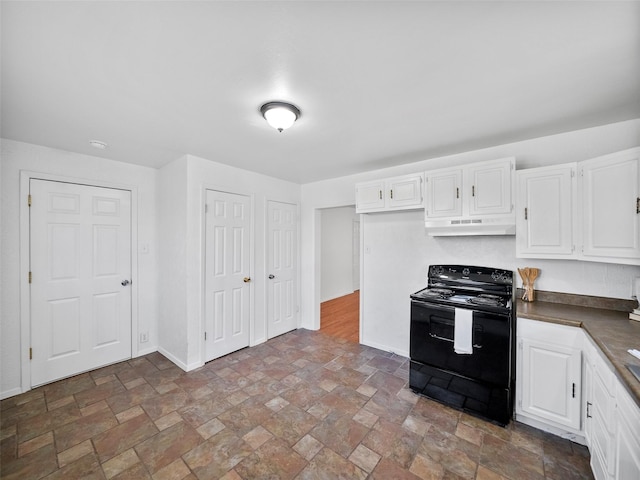 kitchen featuring under cabinet range hood, black range with electric stovetop, white cabinetry, stone finish floor, and dark countertops