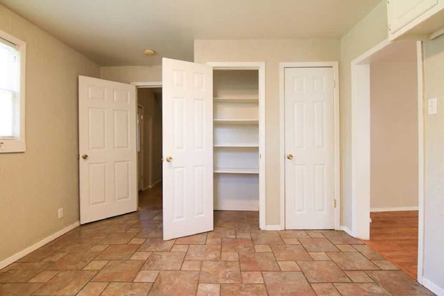 unfurnished bedroom featuring stone finish floor and baseboards