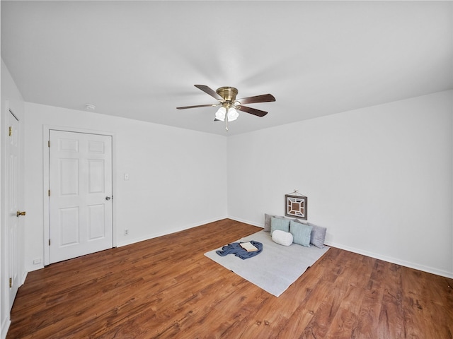 interior space featuring wood finished floors, a ceiling fan, and baseboards