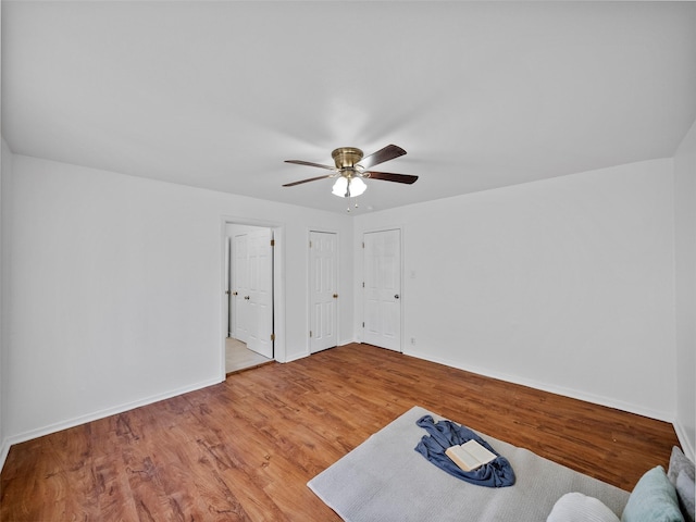 interior space featuring ceiling fan, baseboards, and wood finished floors