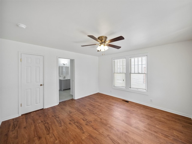 unfurnished room featuring a ceiling fan, baseboards, visible vents, and wood finished floors