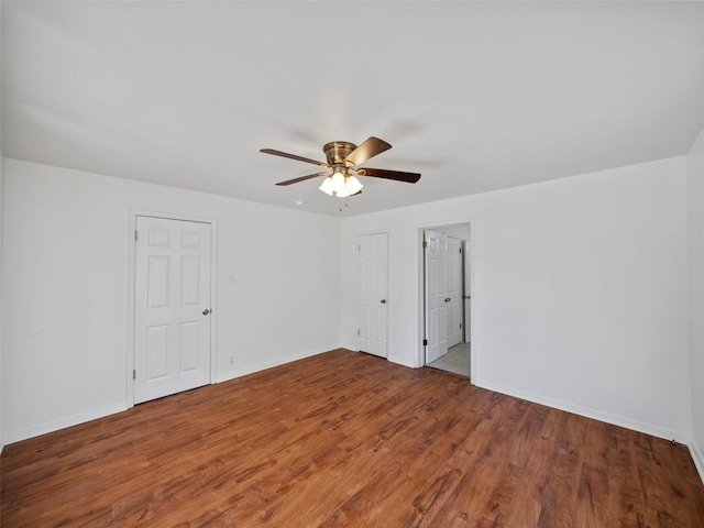 spare room with wood finished floors, a ceiling fan, and baseboards