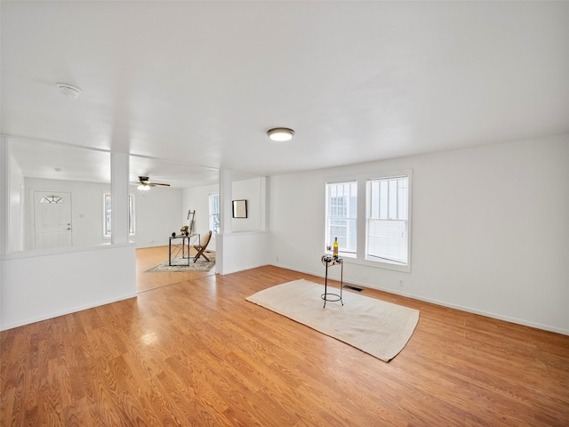 exercise area featuring a ceiling fan, baseboards, visible vents, and wood finished floors