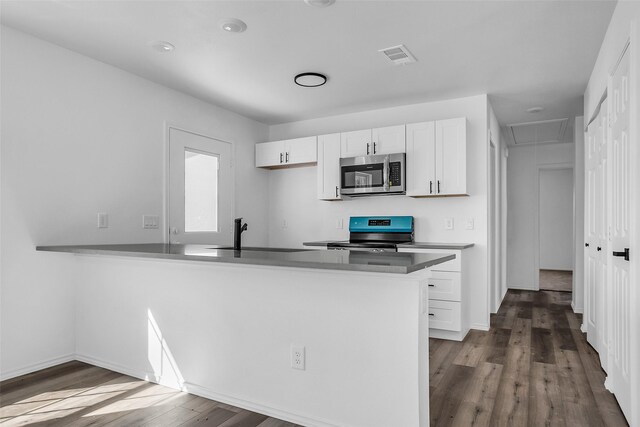 304 S 3rd, Bonham, TX 75418 - kitchen featuring appliances with stainless steel finishes, a sink, white cabinetry, dark wood finished floors, and a peninsula