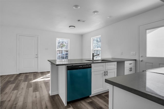 kitchen featuring dark wood-style flooring, dark countertops, visible vents, a sink, and dishwasher