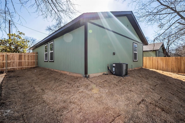 view of side of home featuring fence and central AC