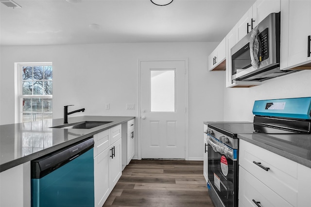 304 S 3rd, Bonham, TX 75418 - kitchen featuring stainless steel appliances, a sink, dark countertops, dark wood-style flooring, and white cabinets