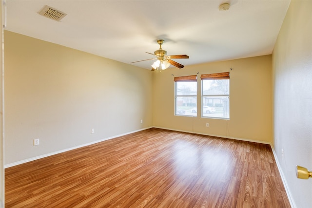 unfurnished room featuring light wood finished floors, baseboards, visible vents, and a ceiling fan