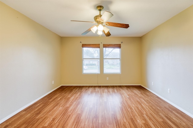 empty room featuring baseboards, a ceiling fan, and light wood-style floors