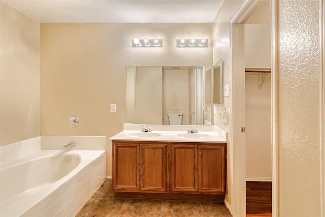 bathroom featuring a garden tub, double vanity, and a sink