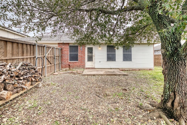 rear view of house with brick siding, a patio, and a fenced backyard