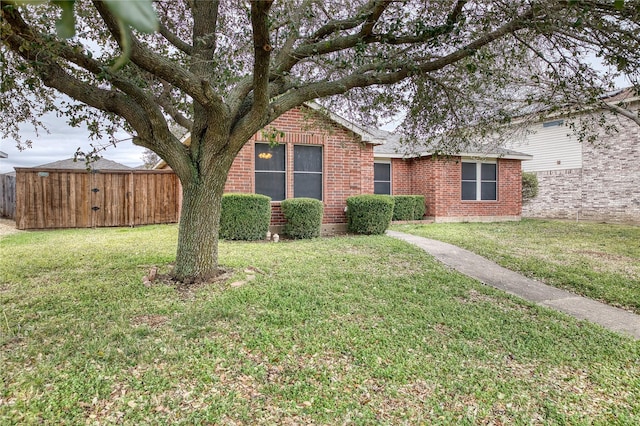 single story home with a front yard, brick siding, and fence