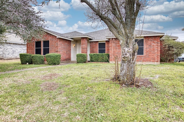 ranch-style home with brick siding, roof with shingles, and a front yard