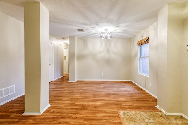 spare room with baseboards, visible vents, and light wood finished floors