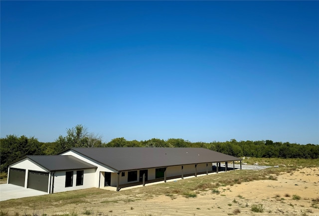 view of front facade with an attached garage, driveway, and metal roof