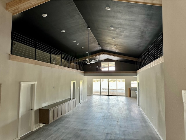 interior space with baseboards, high vaulted ceiling, and wood finished floors